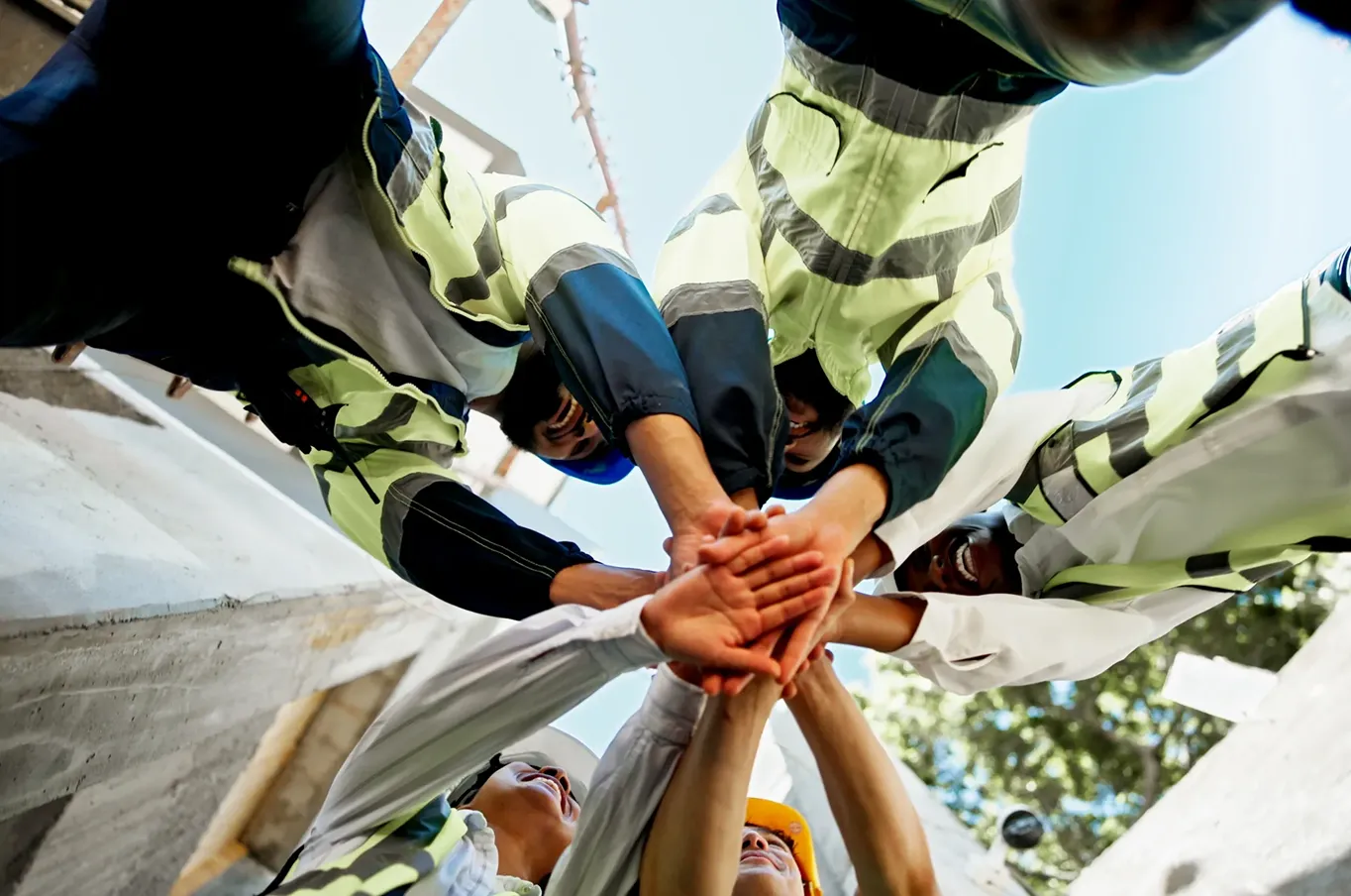 Construction workers joining hands in unity.